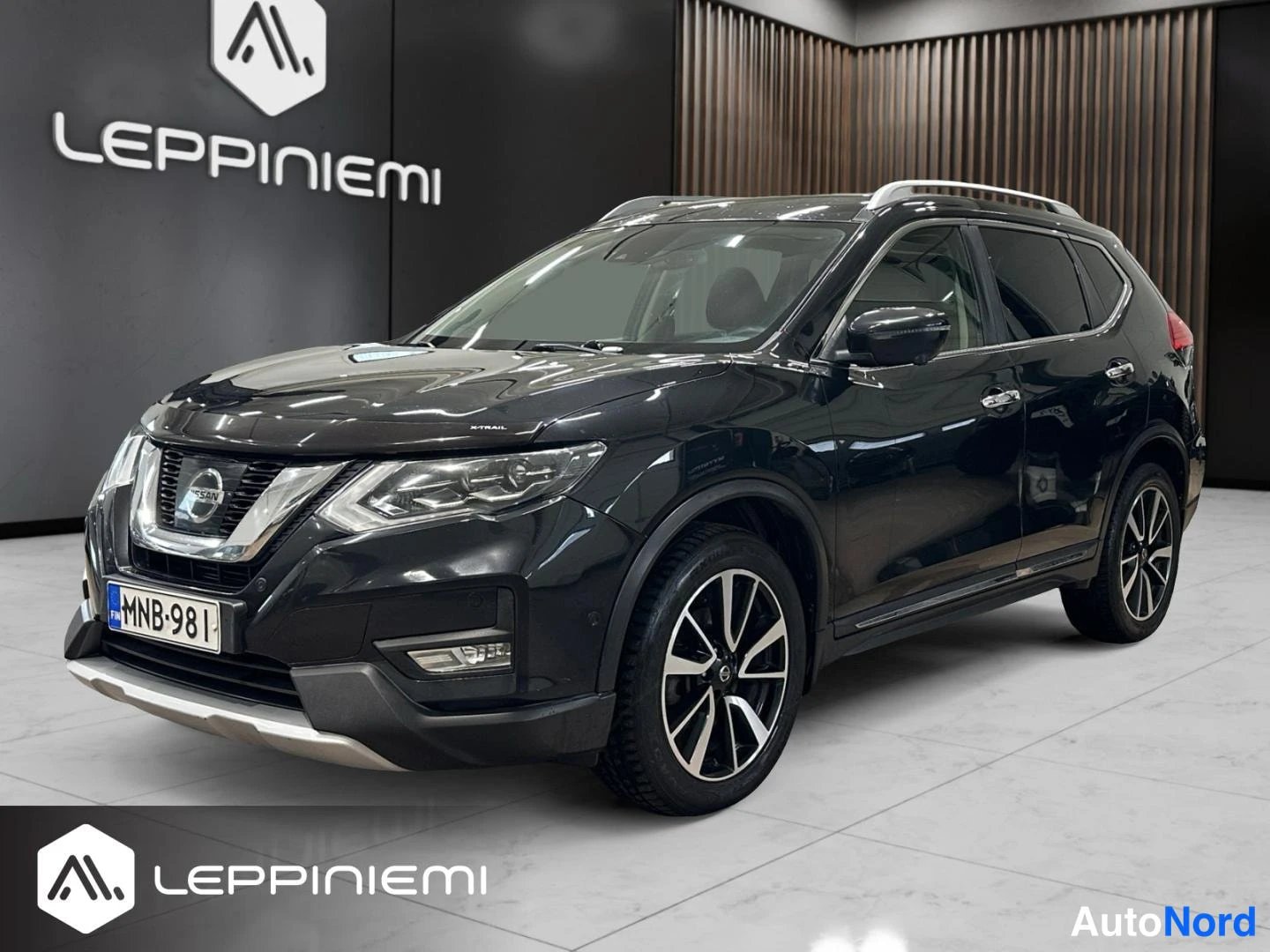 Etuviisto, nokka vasemmalle: Nissan X-Trail etuokoliskulmasta, keulalla vasemmalla; musta runko, viisisakaraiset kevytmetallivanteet ja -rekisterikilpi.