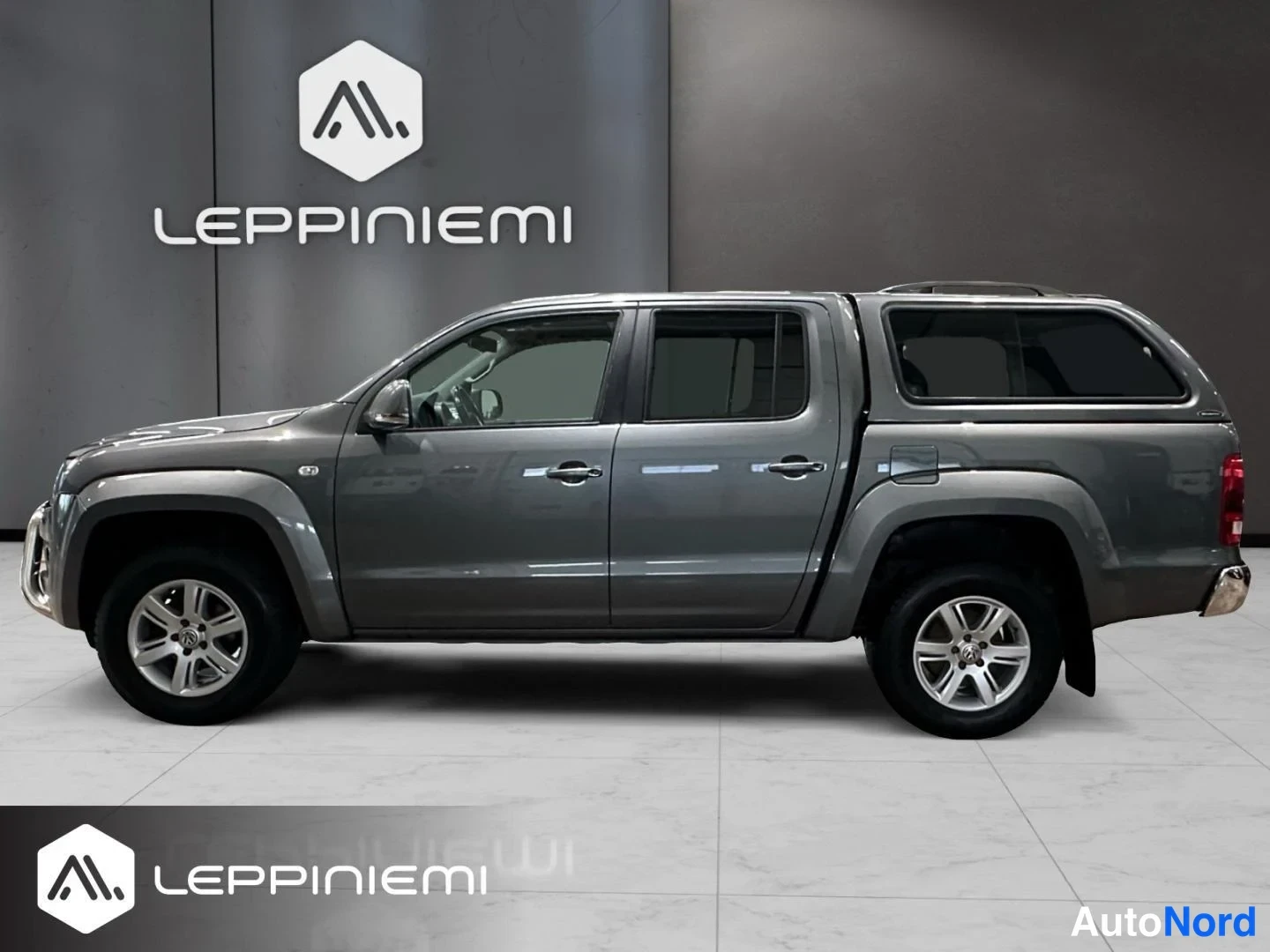 Sivulta: Volkswagen Amarok -nellivuoden avolava sivulta oikealta kuvattuna, tummanharmaa kori ja takakonttiin kiinteä kovakate.