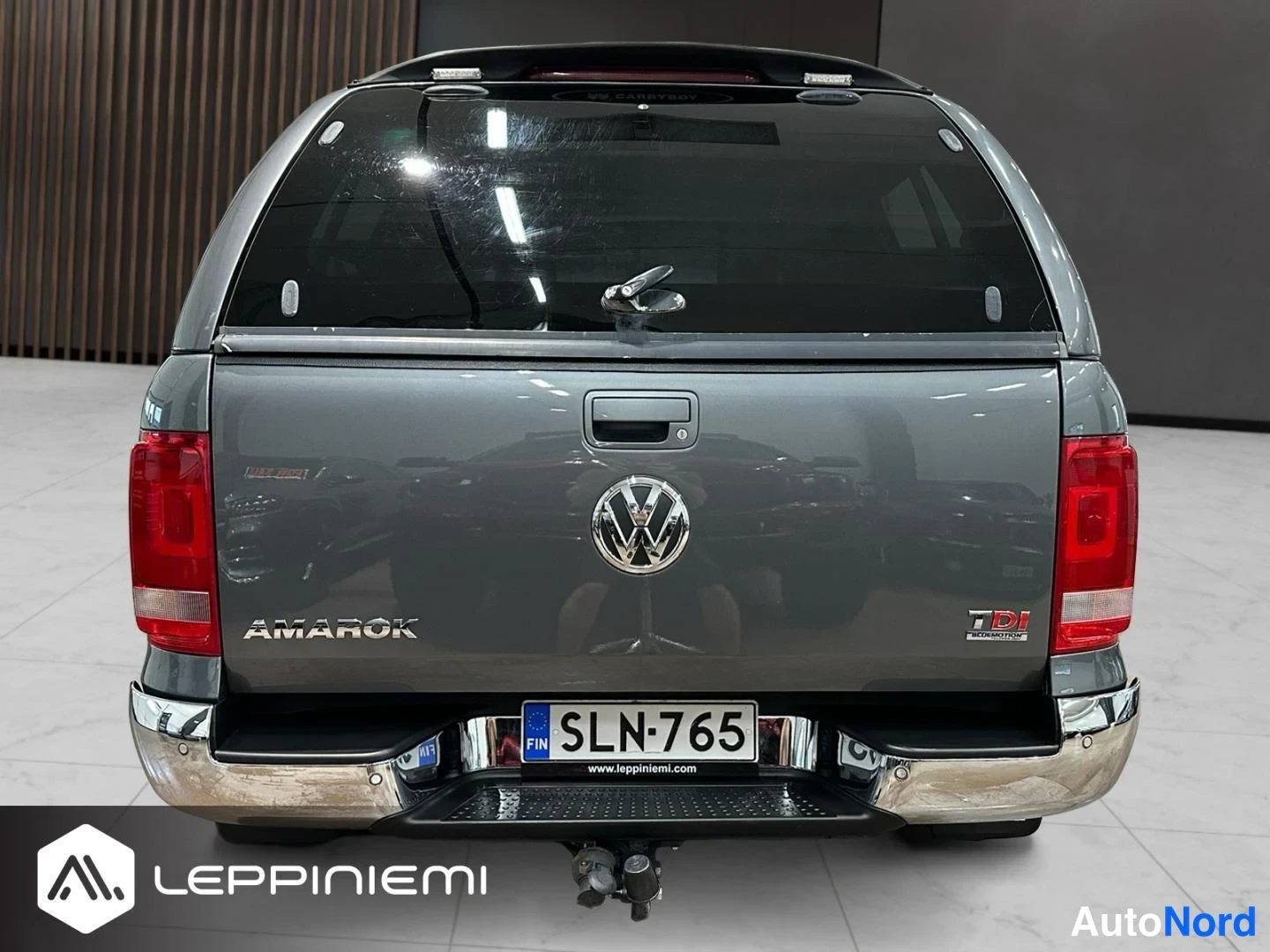 Takaa: Volkswagen Amarok takaa suoraan kuvattuna, tummanharmaa lava, AMAROK- ja TDI-badge, rekisterikilpi ja takaapuveden kytkin.