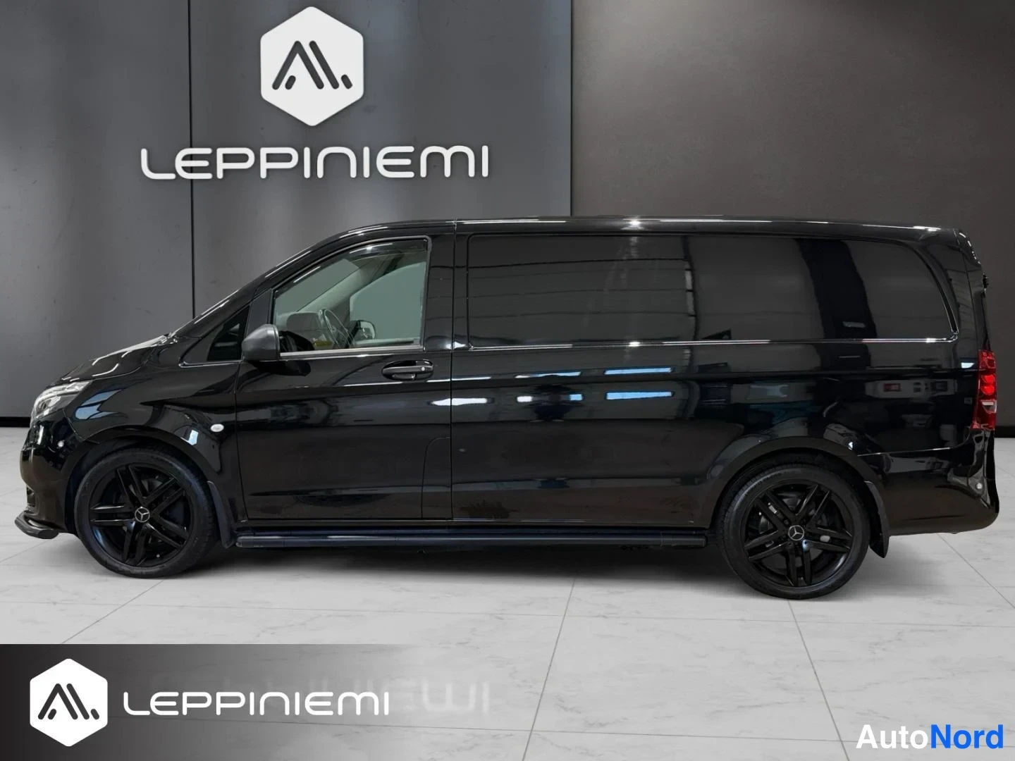 Sivulta: Musta Mercedes-Benz Vito sivunäkymä oikealta puolelta kuvattuna sisätiloissa, mustat kevytmetallivanteet ja tummat takavalojen pinnat.