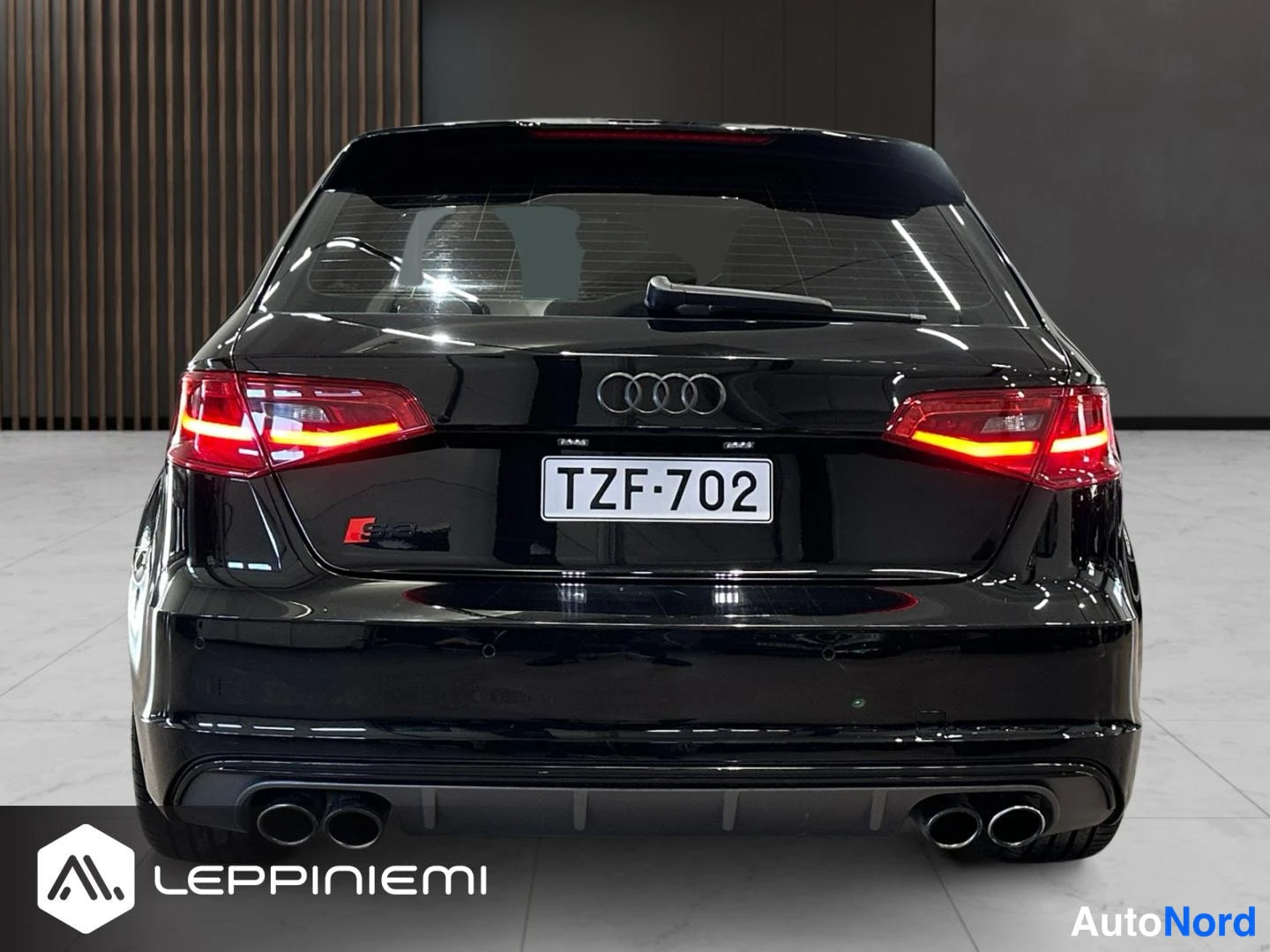 Takaa: Audi S3 Sportback -musta hatchback takaapäin kuvattuna; punaiset takavalot, Audi-merkki rekisterikilven yllä, neljä pakoputkea ja taustasähkö Lasikai takaikkuna