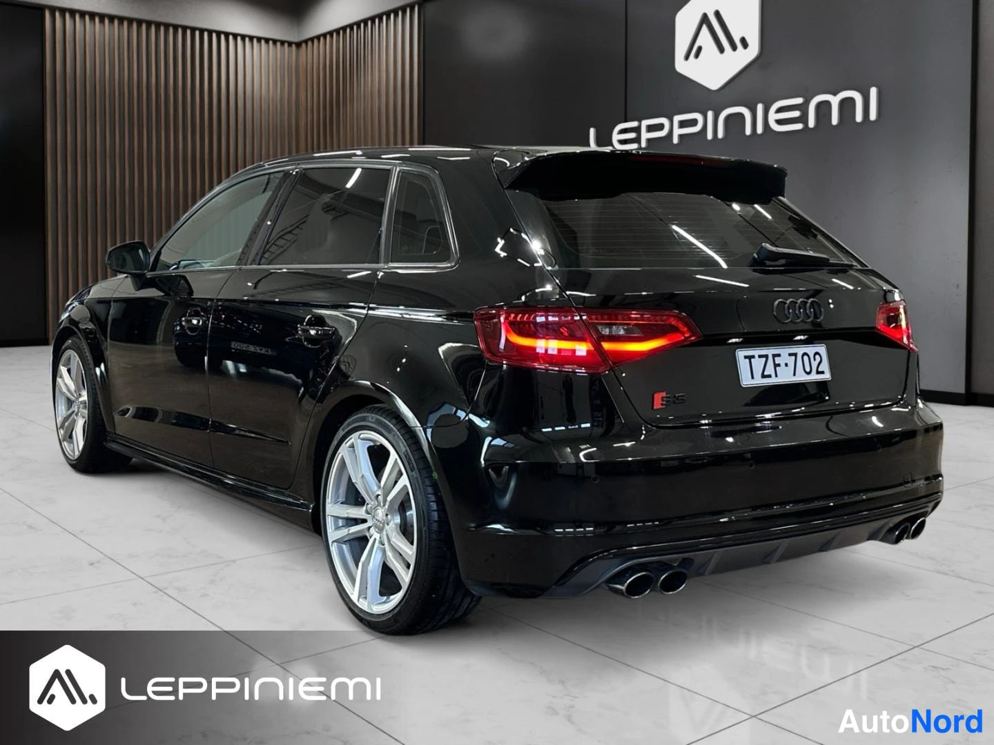 Takaviisto: Musta Audi S3 Sportback taka- ja kylkinäkymässä; punaiset takavalot, -rekisterikilpi, S3-merkki, hopeiset viisikesipyörät ja neljä pakoputkea.
