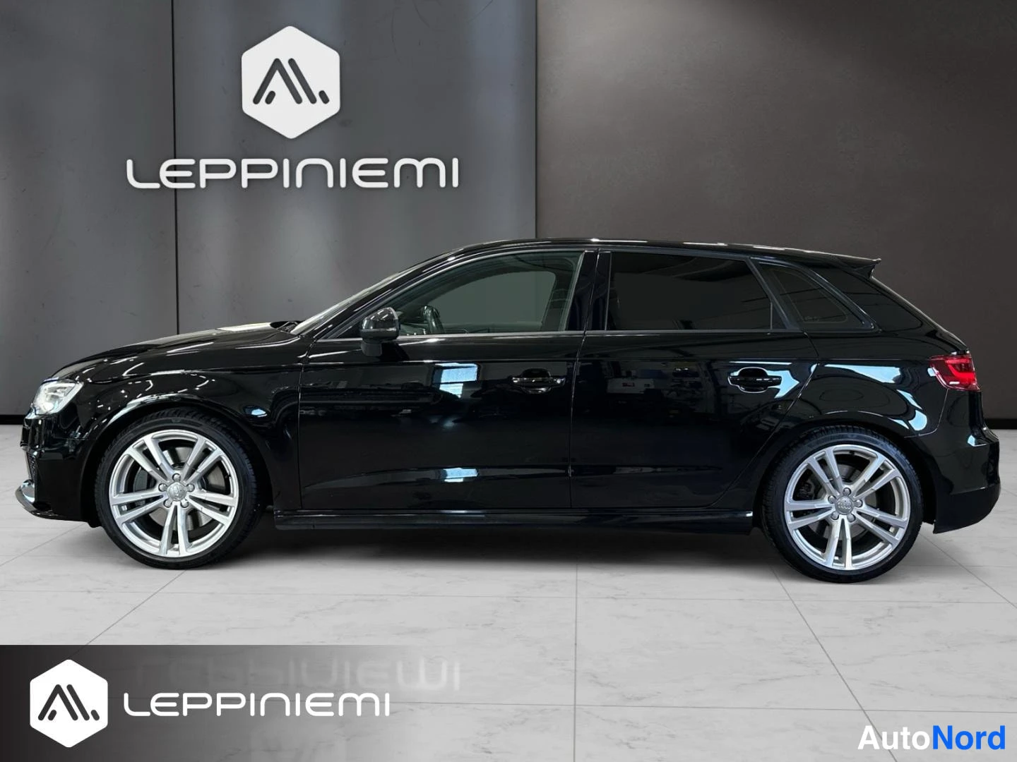 Sivulta: Musta Audi S3 Sportback sivulta; viidennen ovi, hopeiset monihaarukkapyykkit, mustat ikkunat ja kirkas kiiltävä musta maali.