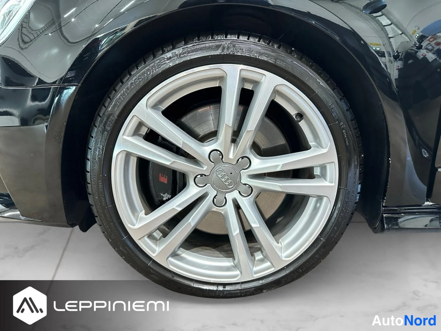 Yksityiskohta: Audi S3 -pyörä lähikuvassa; hopeinen monihaarukka alumiinivanne, Audi-keskuspainike, punainen S-jarrusatula ja Bridgestone-rengas.