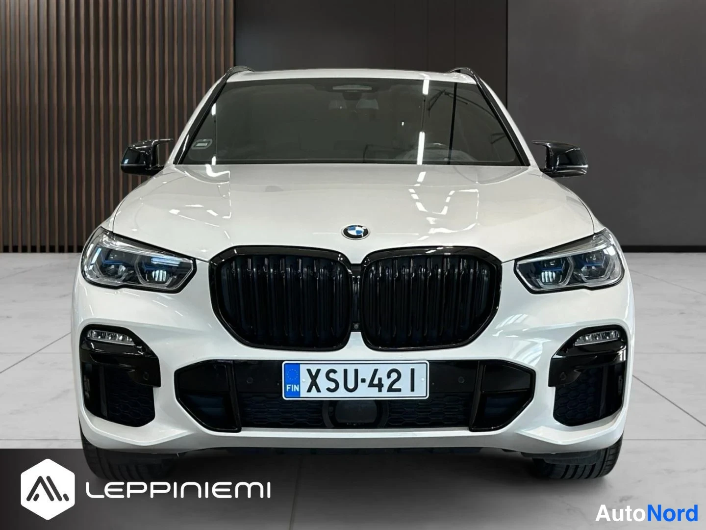 Edestä: Valkoinen BMW X5 suoraan edestä, musta munuaissäleikkö, LED-ajovalot ja rekisterikilpi FIN.