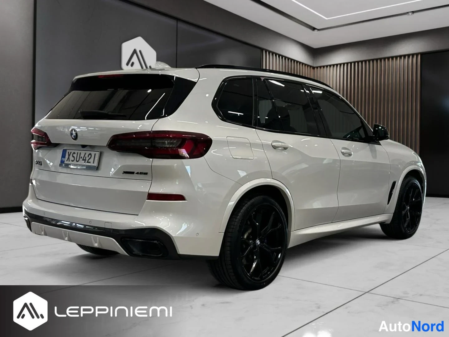 Takaviisto: BMW X5:n takakulma kolmesta neljänneksestä, valkoinen koriväri, mustat kevytmetallivanteet ja rekisterikilpi.
