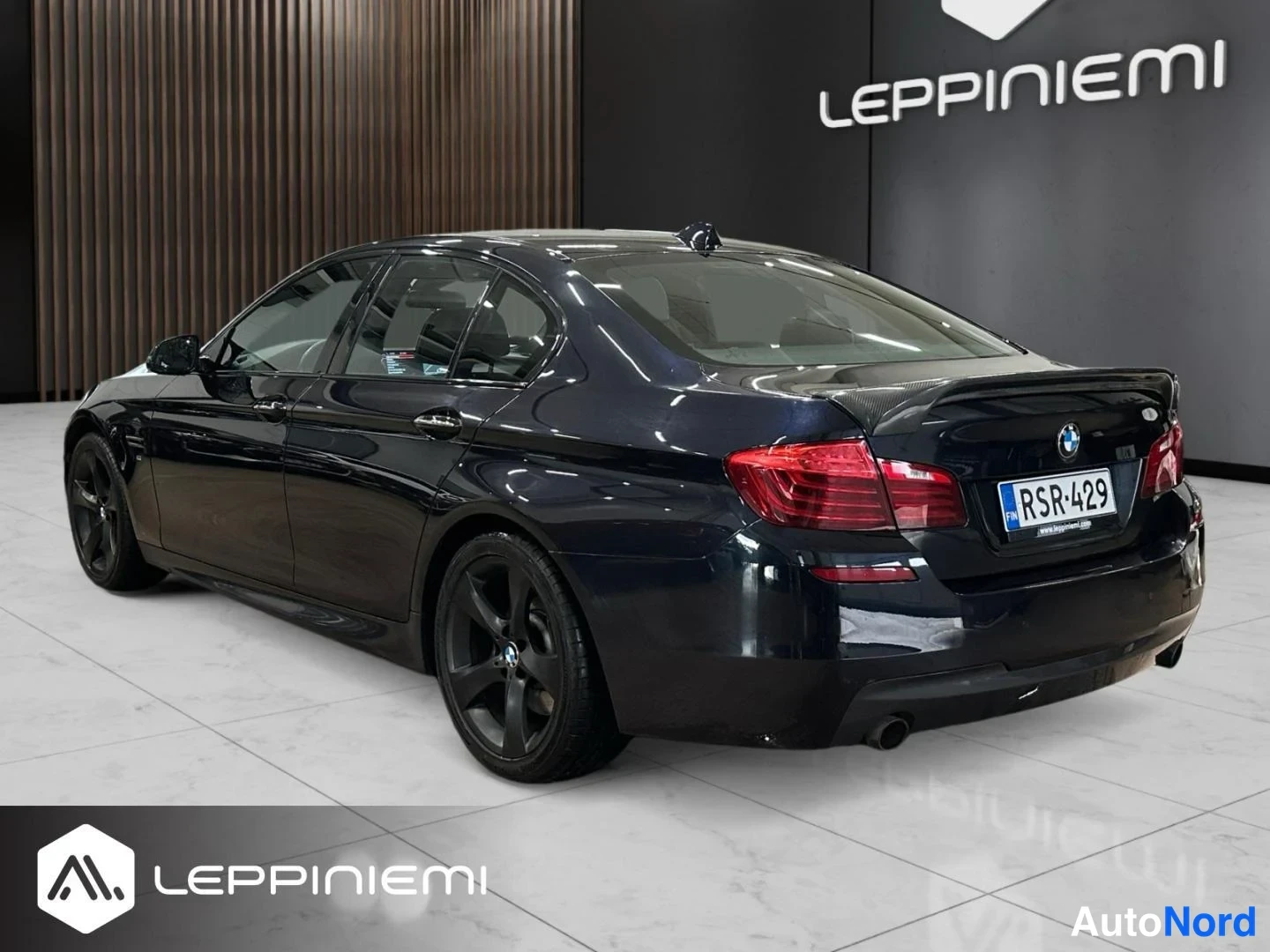Takaviisto: Takakulmanäkymä tummansinisen BMW 5-sarjan sedaanin oikealta puolelta, rekisterikilpi.