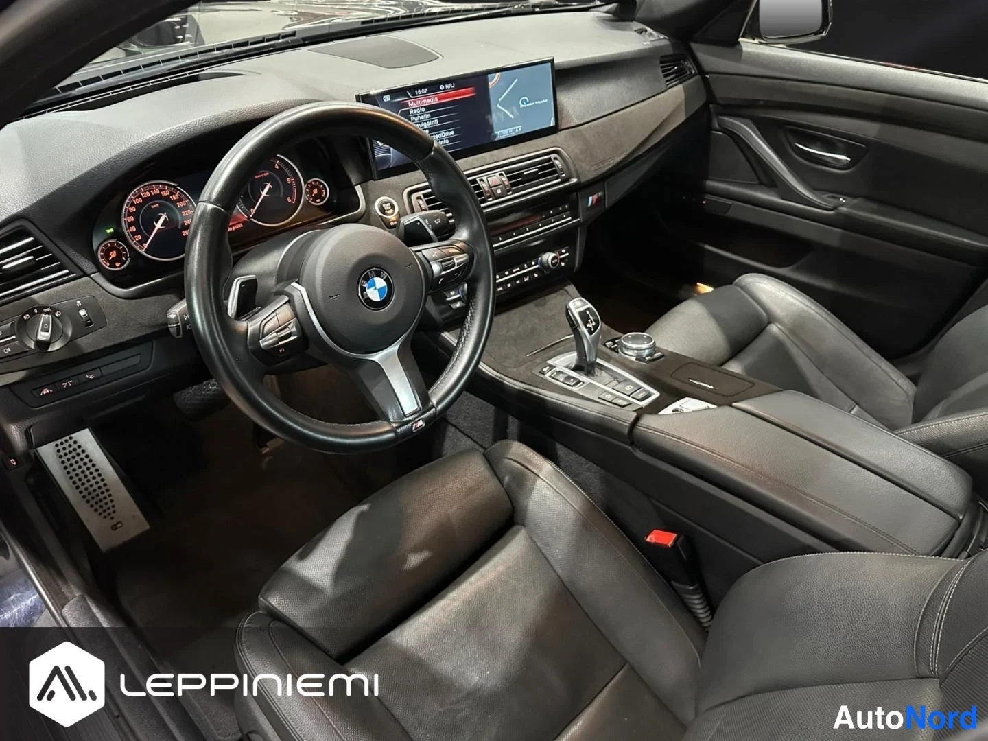 Muu: Auton sisätilat kuljettajan puolelta: BMW-ohjauspyörä, nopeusmittarit, näyttö ja automaattivaihteen valitsin.