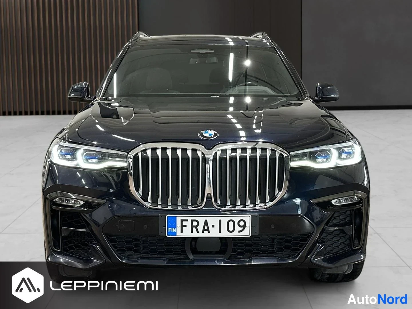 Edestä: Tumma BMW X7 suoraan edestä kuvattuna; maskillinen etugrilli, laser-ajovalot ja rekisteritunnus.