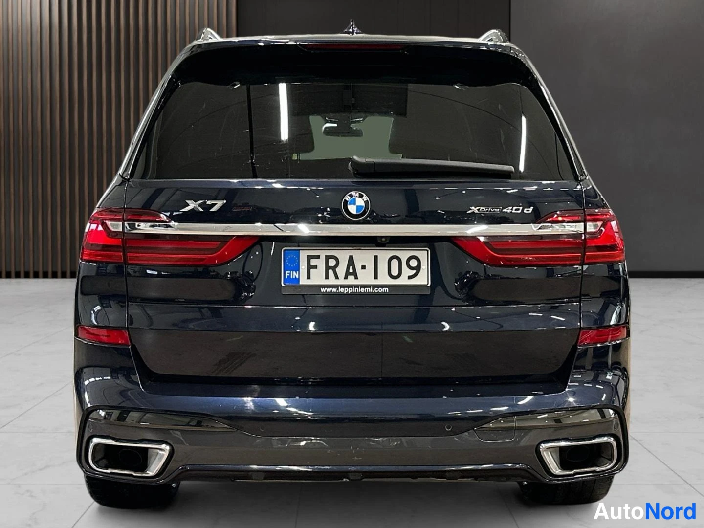Takaa: Auton takaosa suoraan takaa: BMW X7 -merkinnät, sininen ja punainen takavalojen poikki menevä kromilista, rekisterikilpi ja kaksiosaiset pakoputkistorit. Korin
