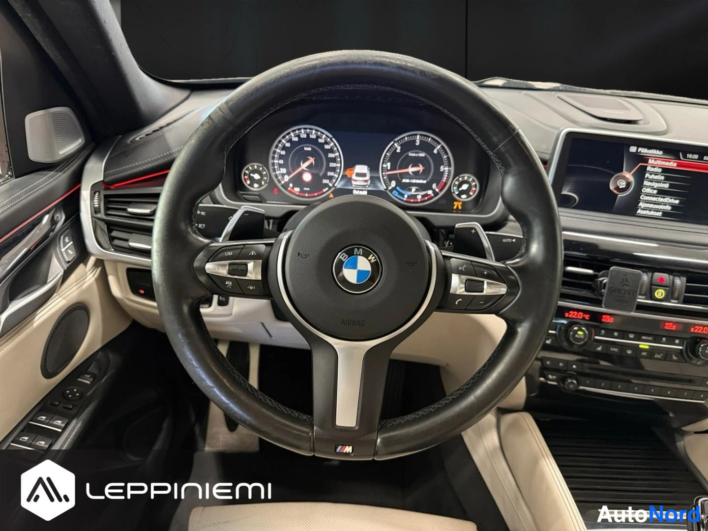 Muu: Lähikuva BMW-ohjauspyörästä ja digitaalisesta mittaristosta; M-merkki ohjauspyörän alareunassa.