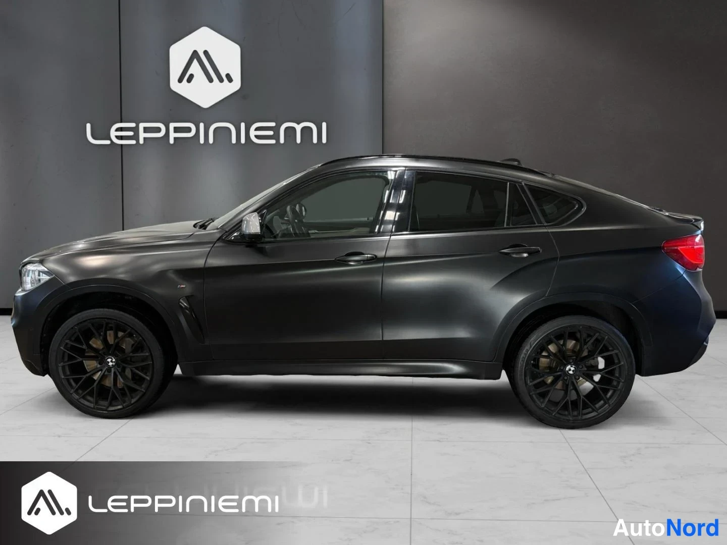 Takaviisto: Musta BMW X6 kulmaan kuvattuna takaa oikealta, takavalo ja mustat kevytmetallivanteet näkyvät.