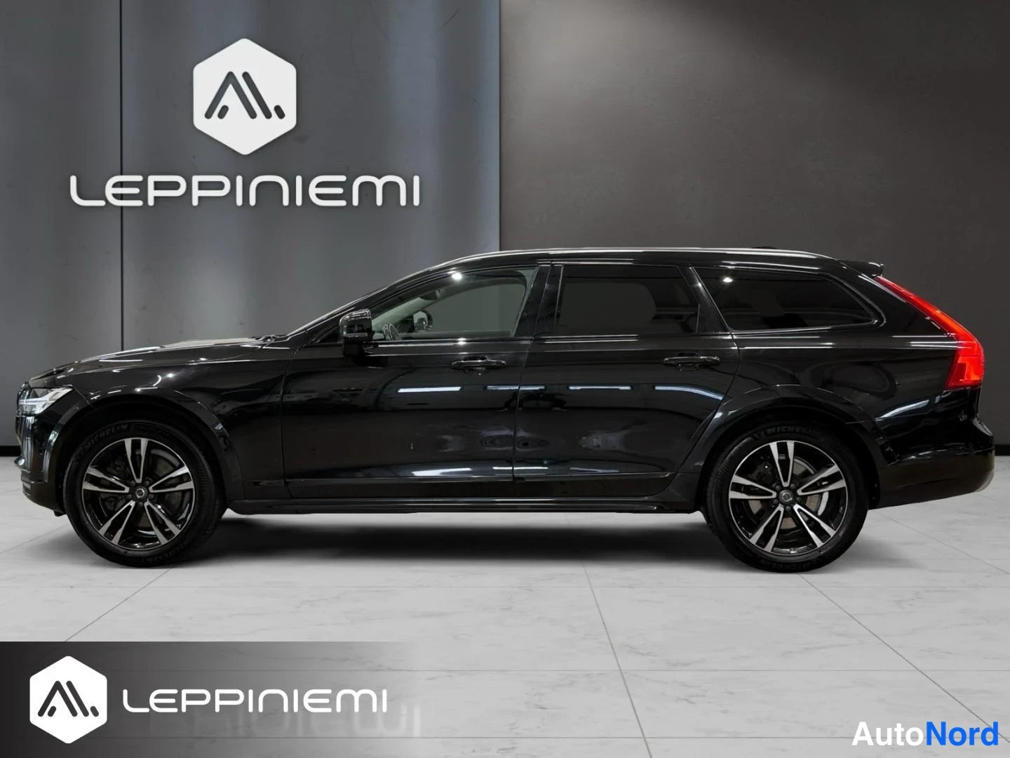 Sivulta: Mustan Volvo V90 -farmarin sivuprofiili oikealta puolelta nähtynä sisätiloissa.