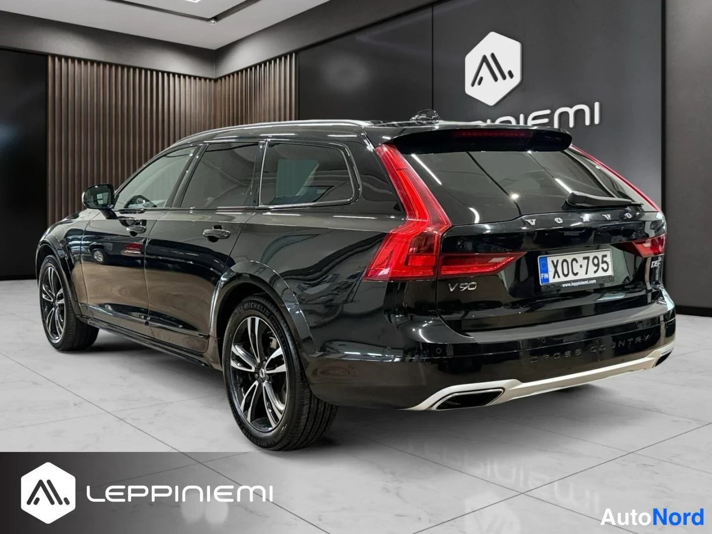 Takaviisto: Musta Volvo V90 farmariauto takaa-oikealta kuvattuna näkyvissä takavaloissa, kannessa V90-merkintä ja rekisterikilpi, Cross Country-teksti puskurissa.
