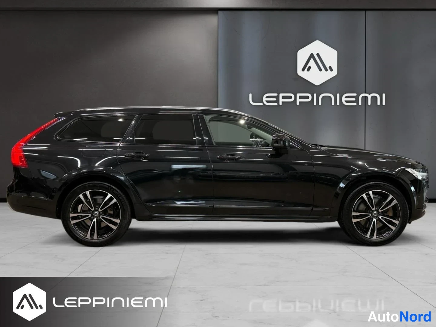 Sivulta: Musta Volvo V90 Cross Country farmariauto sivulta vasemmalta kuvattuna, neljä ovea näkyvissä, mustat kevytmetallivanteet.