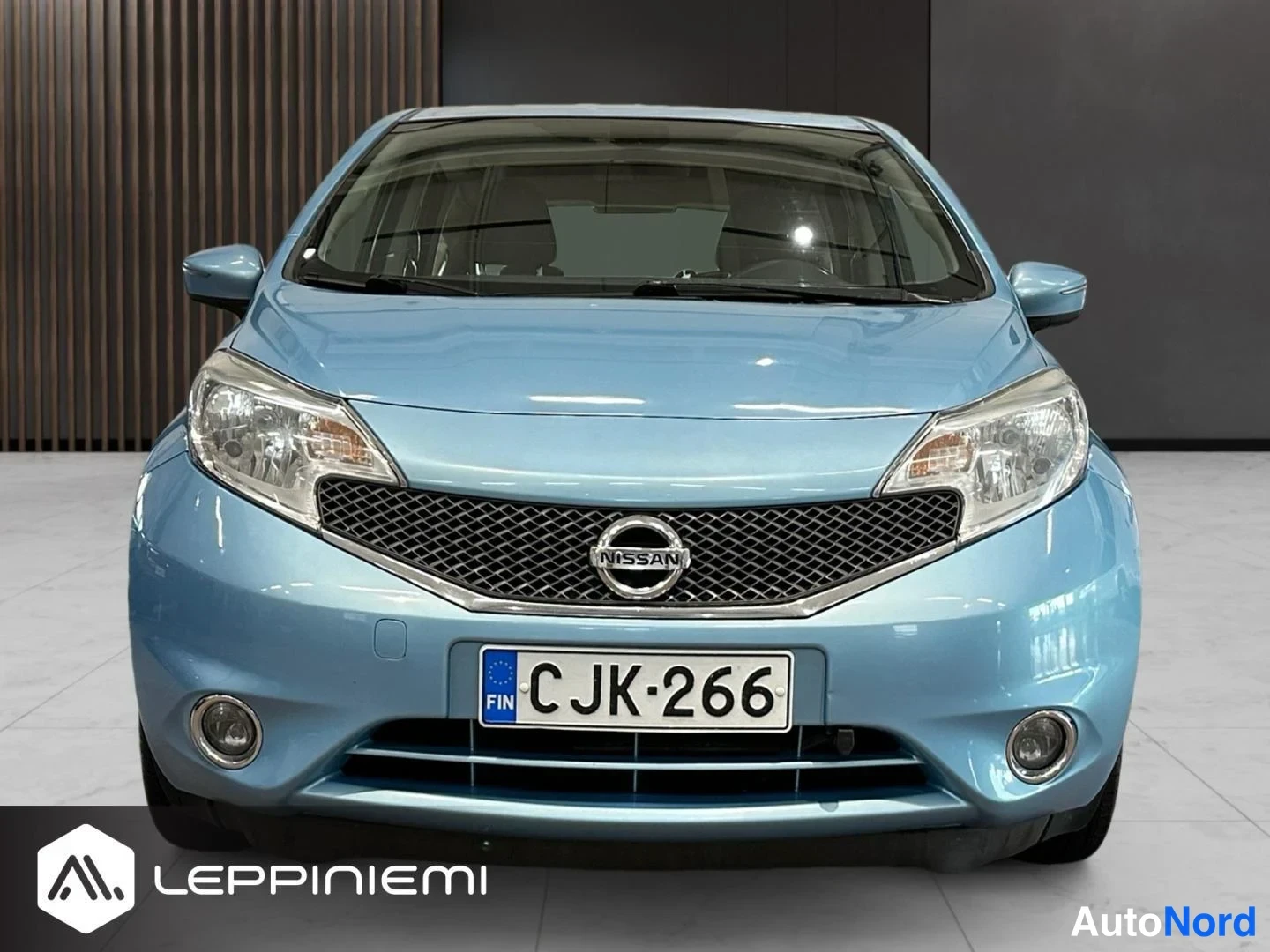 Edestä: Sinisen Nissan Noten etupää suoraan edestä, etumoottorin kansi ja etusuoja näkyvät