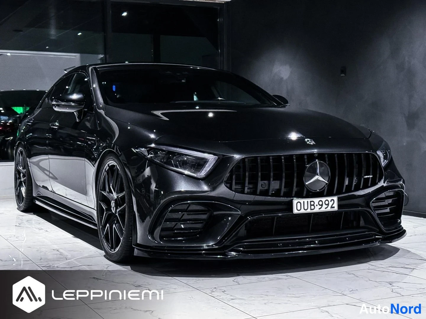 Etuviisto, nokka oikealle: Mustan Mercedes-Benz CLS -auton etukulmanäyttö oikealta, rekisterikilpi, mustat vanteet.