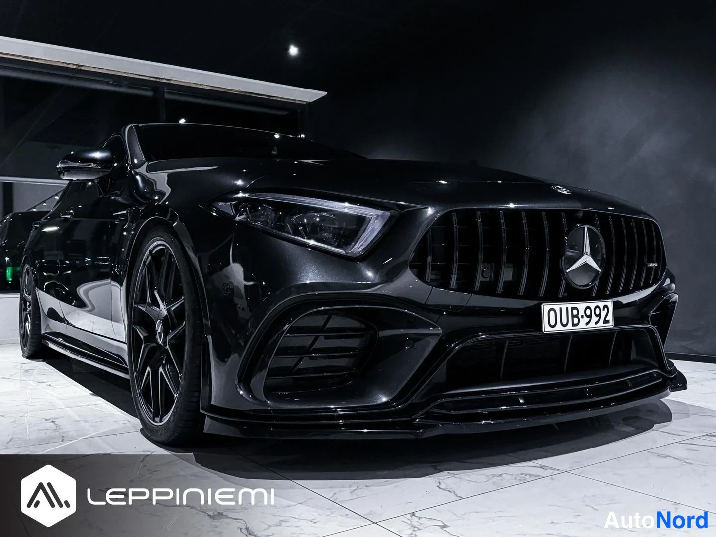 Etuviisto, nokka oikealle: Musta Mercedes-Benz CLS edestä vasemmalta kuvattuna, näkyvät etusäleikkö, Mercedes-tähti, ajovalot, -rekisterikilpi ja mustat kevytmetallivanteet.