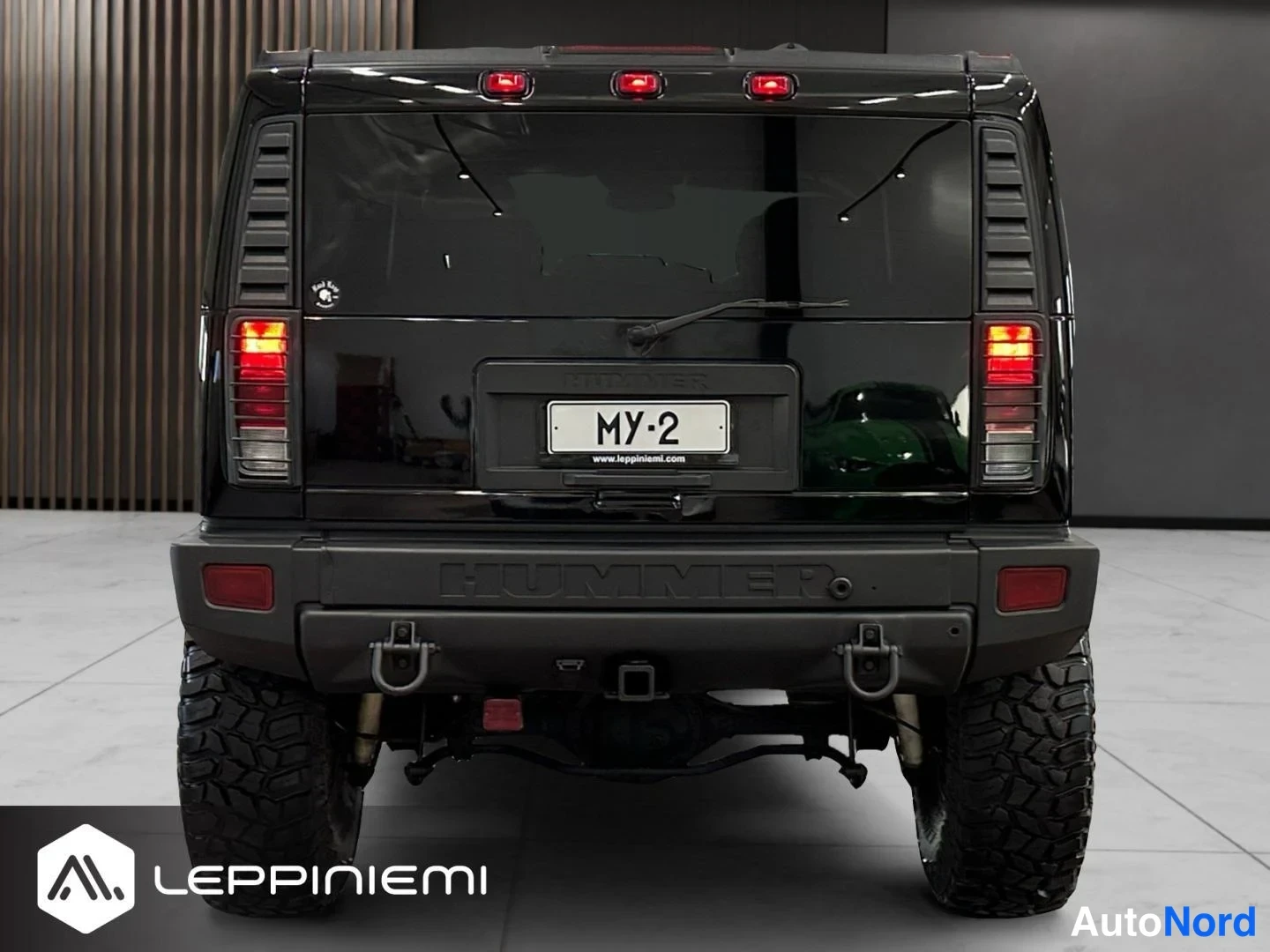 Takaa: Mustan Hummerin takanäkyvissä rekisterikilpi MY-2, punaiset takavalot ja HUMMER-tekstin sisältävä takapuskuri.
