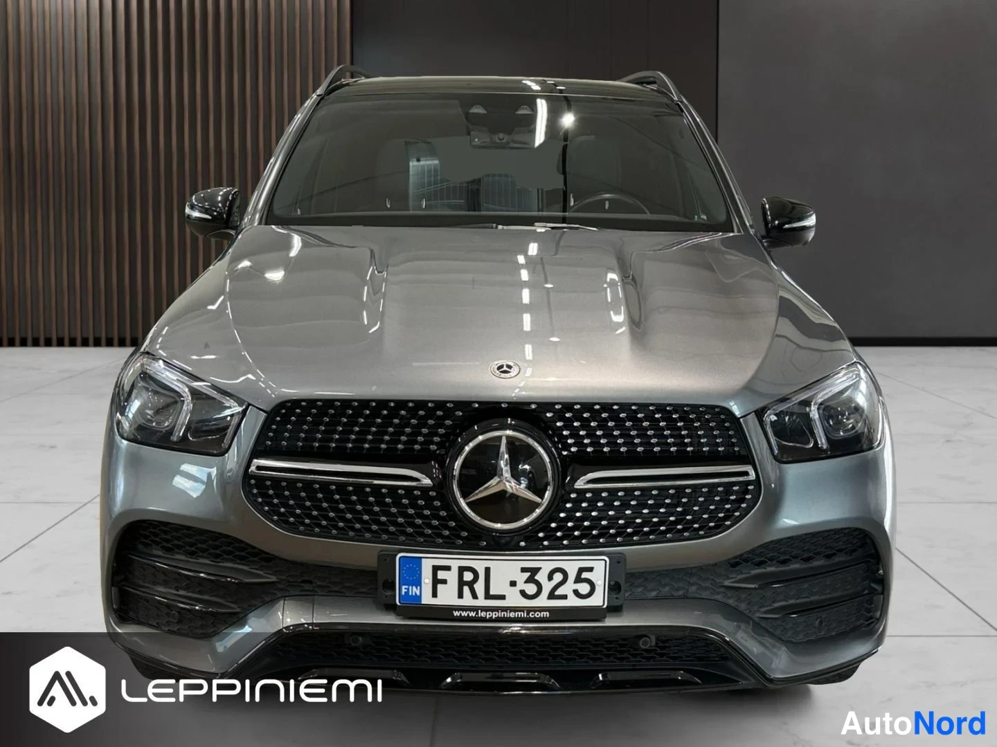 Edestä: Mercedes-Benz GLE:n etunäkymä harmaalla maalilla, takaraspyörän kotelossa selvä kolhi.