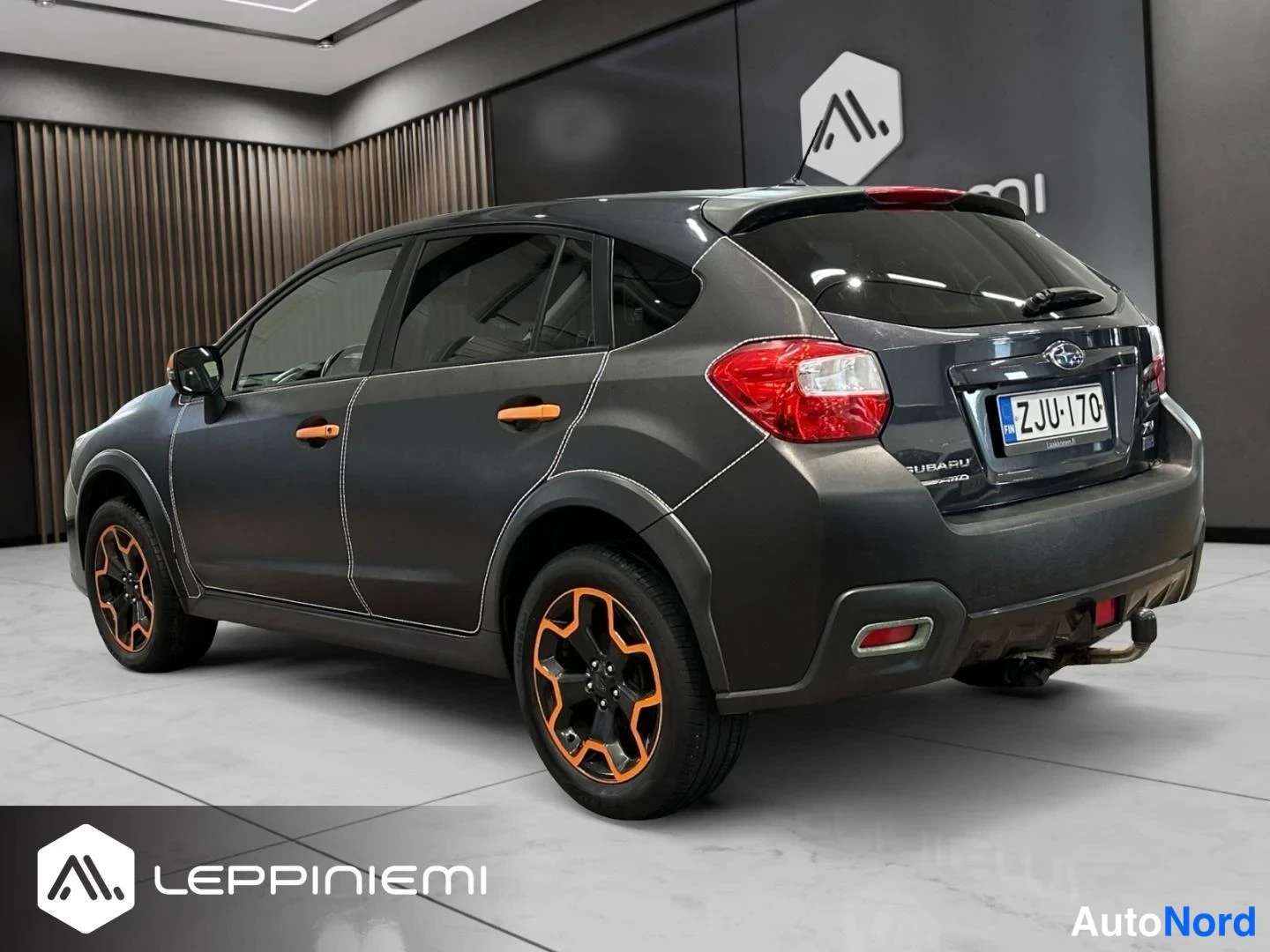 Takaviisto: Subaru XV:n takakulma kolmesta neljäsosasta oikealta, rekisteritunnus, oranssit vanteet ja oranssit ovikahvat.