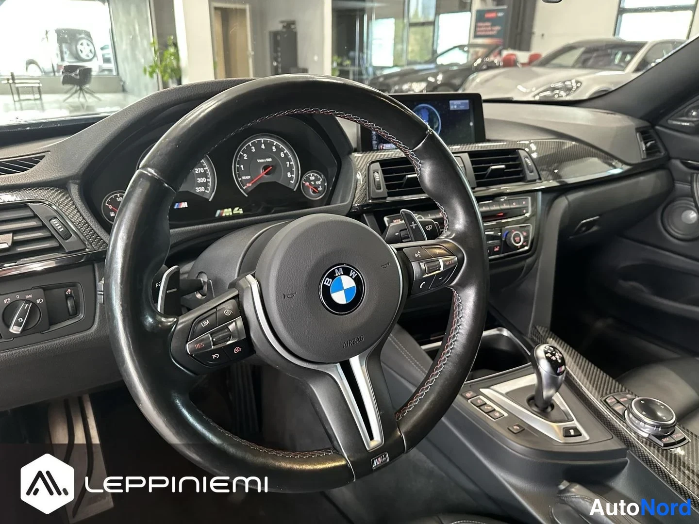 Etuviisto, nokka vasemmalle: Ohjaamoon suunnattu sisäkamera: BMW-ohjauspyörä, M4-merkitty mittaristo, hiilikuitupanelit, näyttö ja automaattivaihteen valitsin.