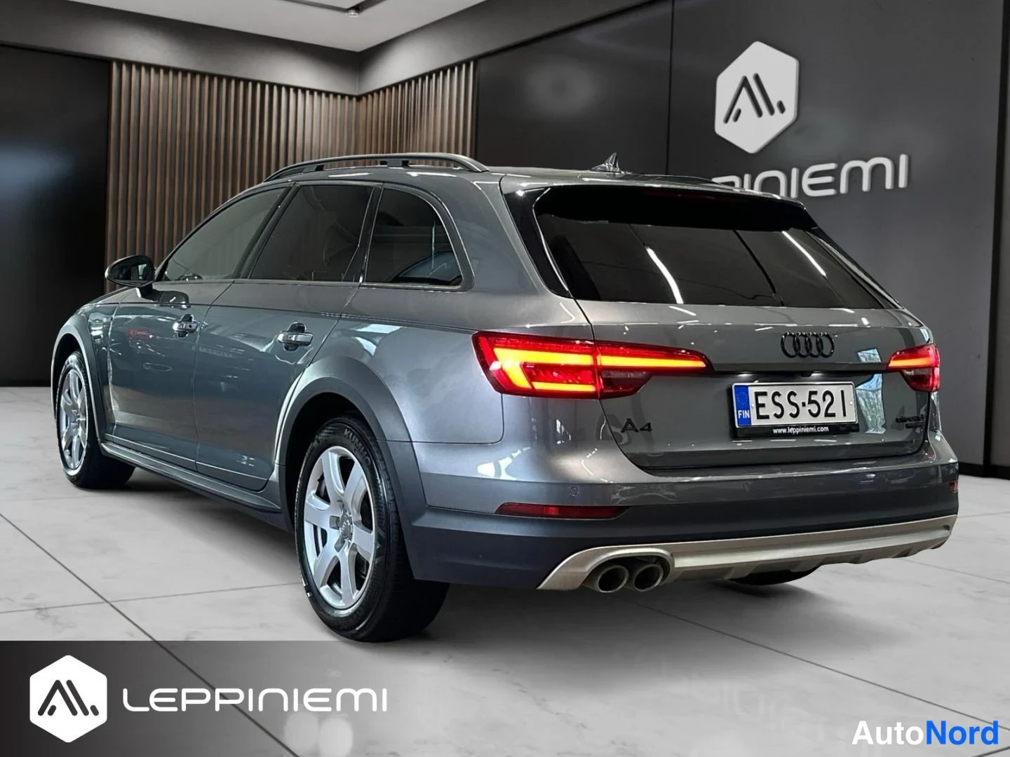 Takaviisto: Harmaa farmariauto takaa viistosti vasemmalta nähtynä, perävaakat paljaat, rekisteritunnus.