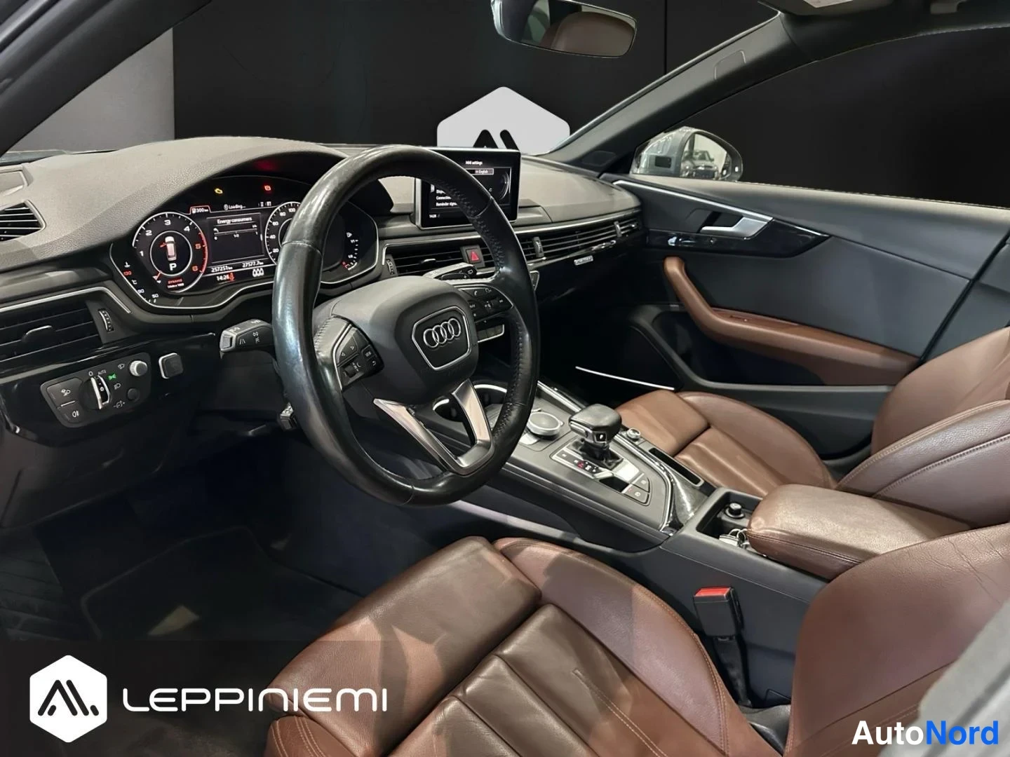 Edestä: Ohjaamo kuljettajan puolelta: Audi-mk-märki Ohjauspyörä, digitaalinen kojelauta näyttää P-tilan, keskikonsolilla vaihteenvalitsin, radio- ja karttanäytöllä puna