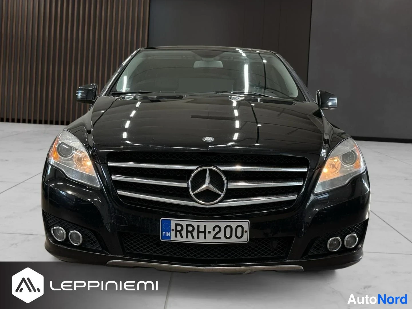 Edestä: Mustan Mercedes-Benz R -mallin suora etunäkymä, keulavälikkeen Mercedes-tähti ja rekisteritunnus.