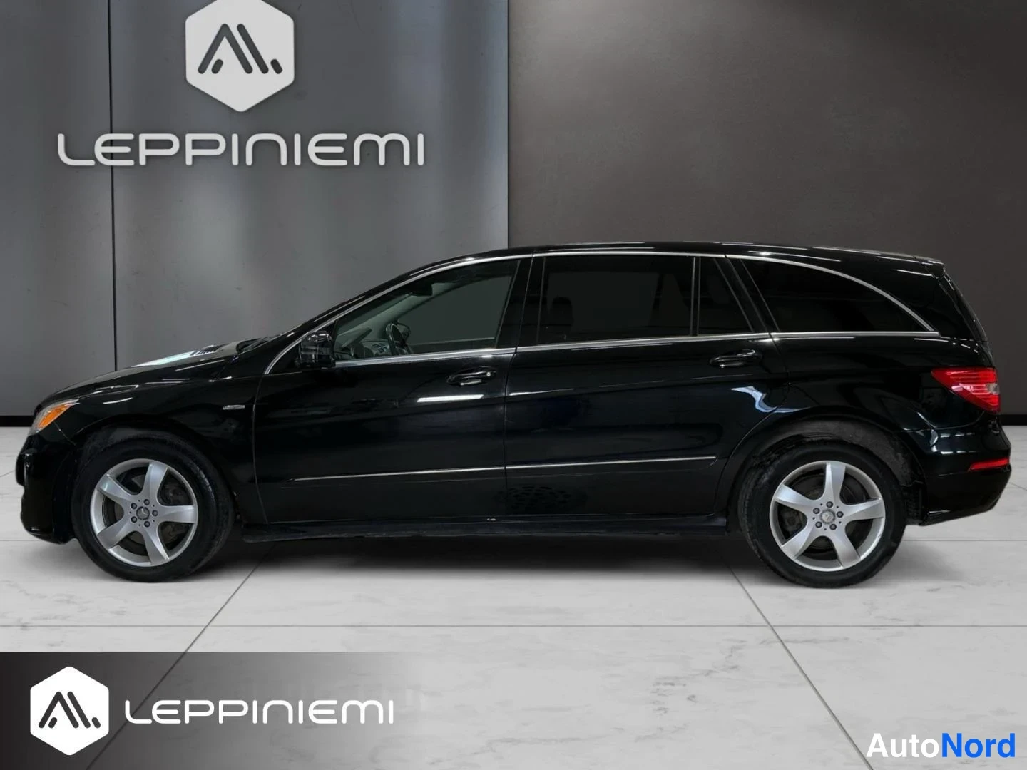 Takaviisto: Mercedes-Benz R:n profiilinäkymä vasemmalta: musta pitkä farmarikori, kromilista oven alaosassa ja hopeiset viisipuujanteet.
