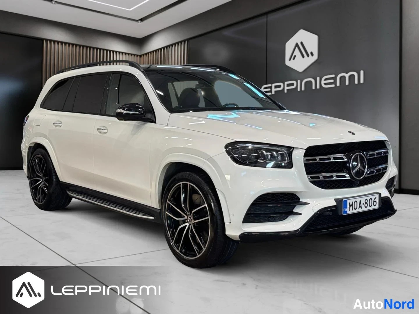 Etuviisto, nokka oikealle: Valkoinen Mercedes-Benz GLS etuviistosta oikealta, rekisteritunnus, tummat kevytmetallivanteet ja peltikate.