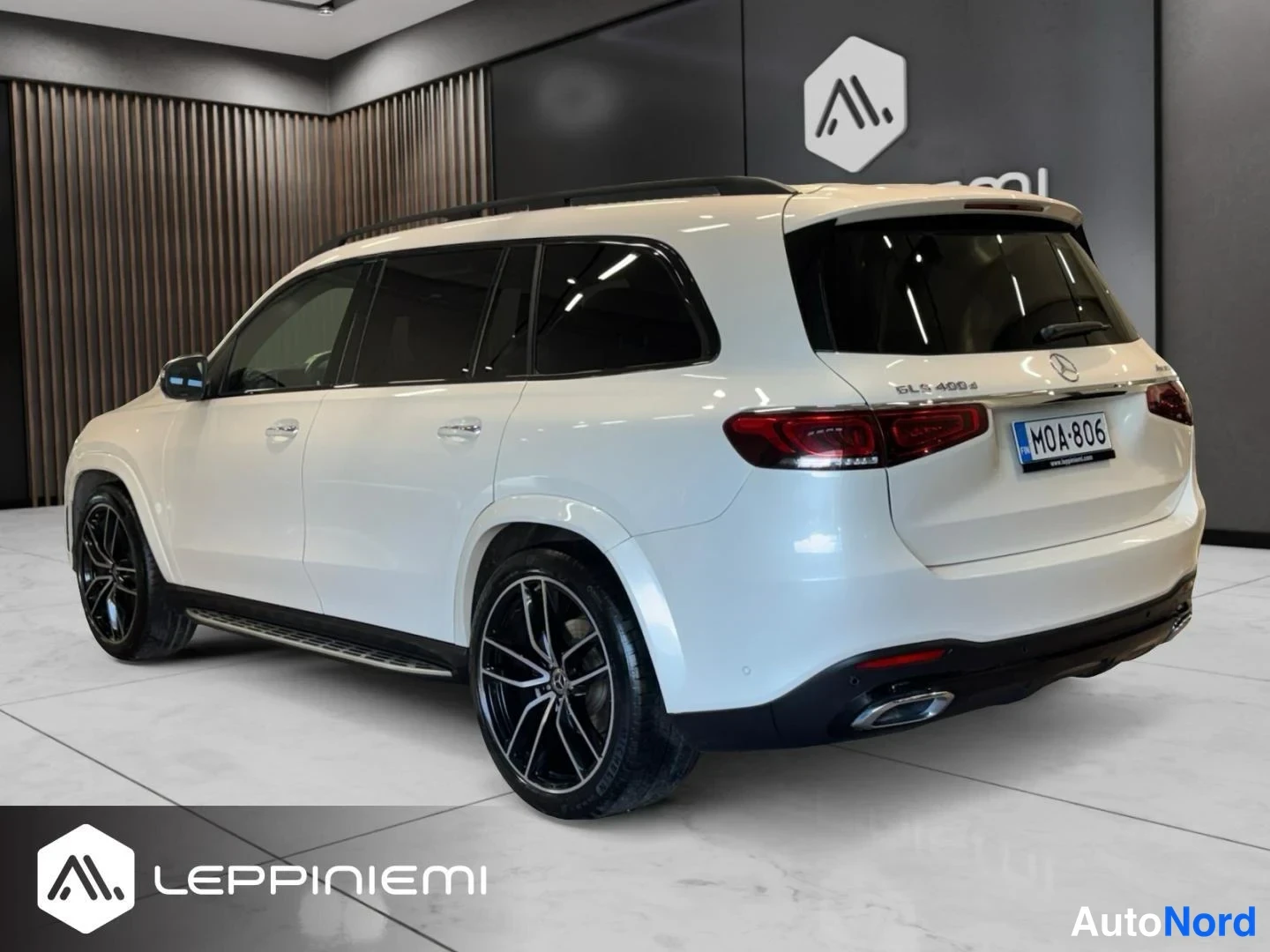 Takaviisto: Valkoinen Mercedes-Benz GLS takaa-kolmasosan kulmasta, rekisterikilpi, mustat/viistetyt kevytmetallivanteet ja takavalot näkyvät sisätiloissa.
