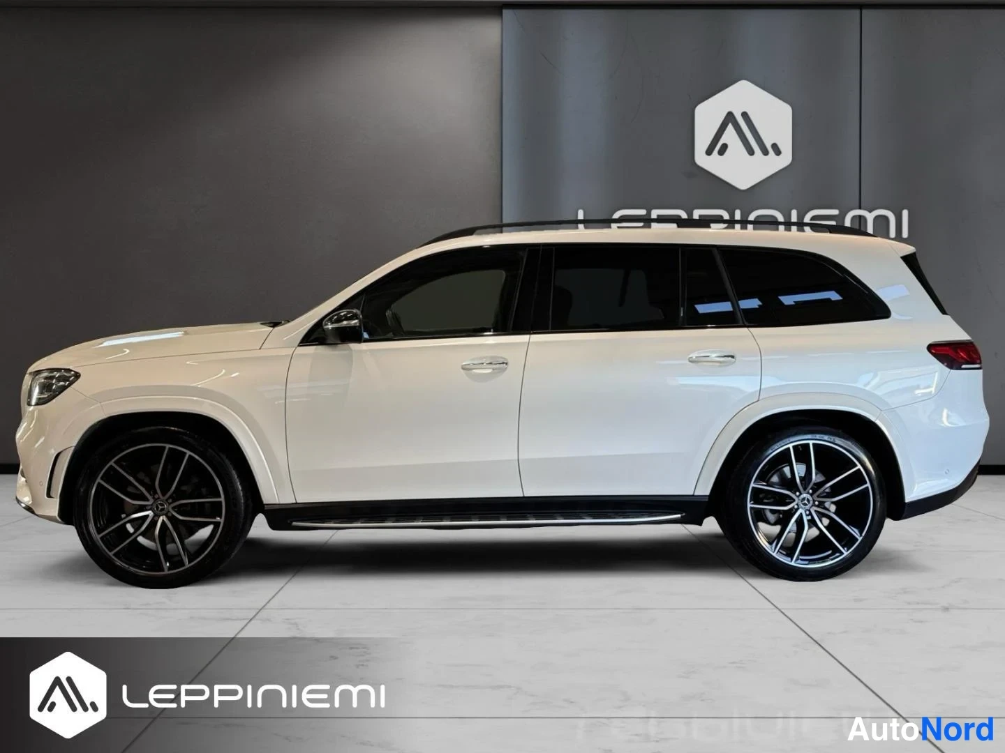 Etuviisto, nokka vasemmalle: Valkoinen Mercedes-Benz GLS -mallin SUV sivulta etukulmasta, mustat vanteet ja kattotelineet.