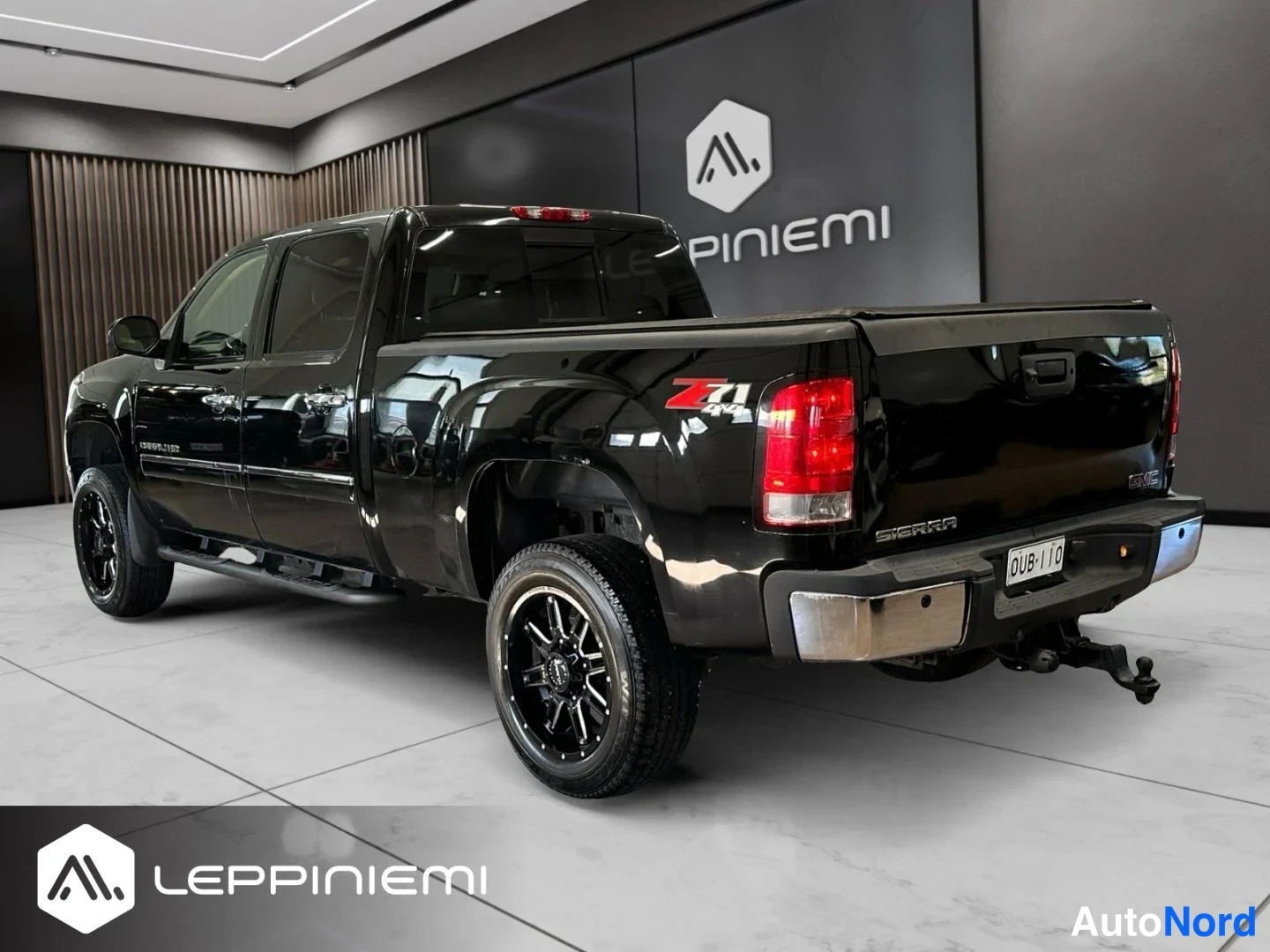 Takaviisto: Mustan avolavakulma-autin takakulma showroomissa, takana Z71 4x4 -tarro ja SIERRA-teksti, rekisterikilpi.
