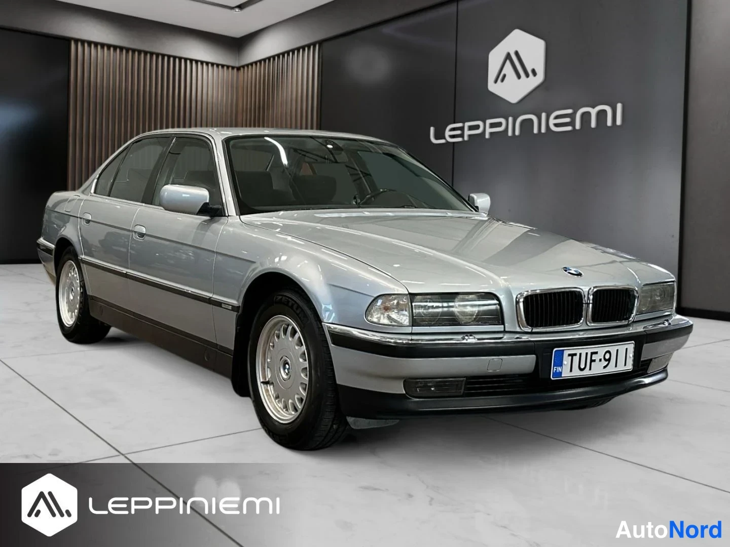 Etuviisto, nokka oikealle: Hopeanvärinen BMW 7 -sarjan sedan Etelärannan autonmyyntitilassa, etukulma oikealta kuvattuna, rekisteritunnus.