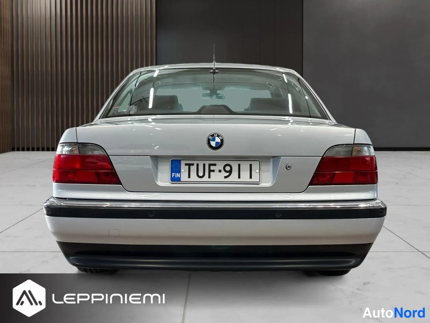 Takaa: BMW:n takapää suoraan takaa, BMW-merkki, punaiset takavalot ja rekisteritunnus.