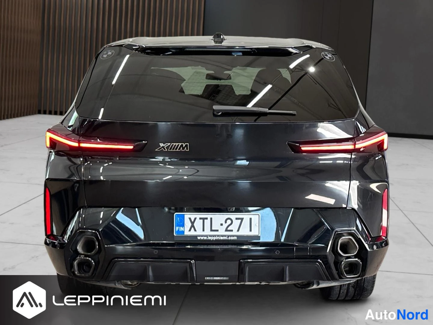 Takaa: Mustan BMW XM:n takanäkö: LED-pysäköintivalot, X M -merkintä, rekisterikilpi ja neljä pakoputkea.