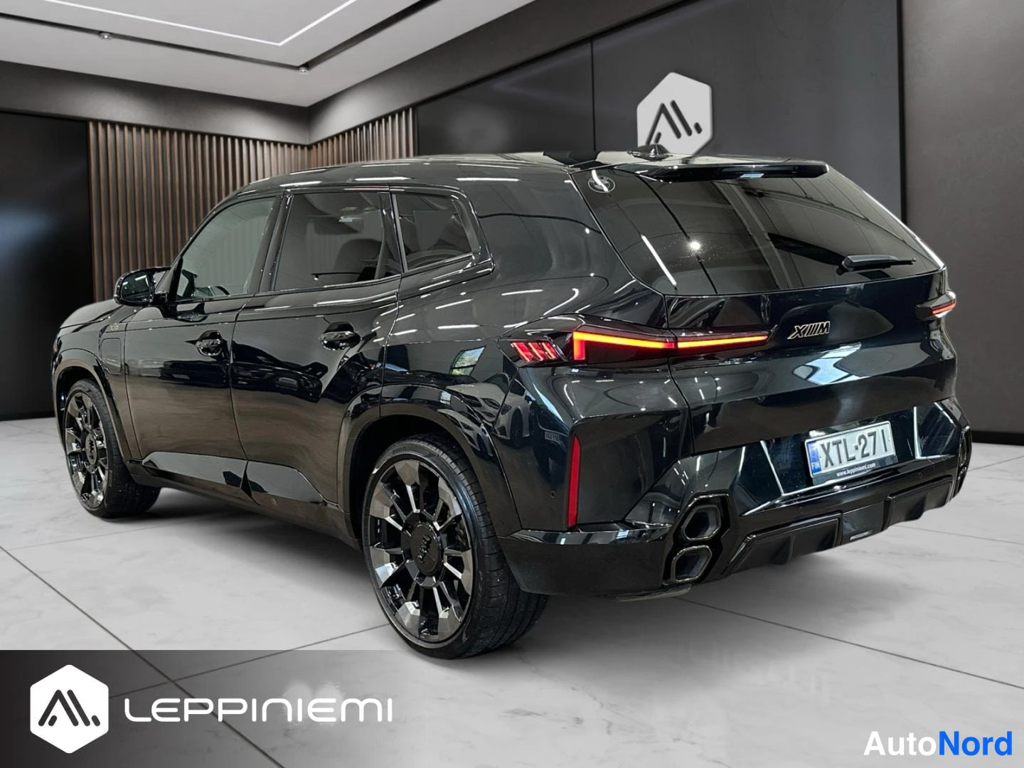 Takaviisto: Musta BMW XM takaa viistosti oikealta kuvattuna; rekisterikilpi, punaiset jarrusatulat ja suuret tummat vanteet näkyvät.