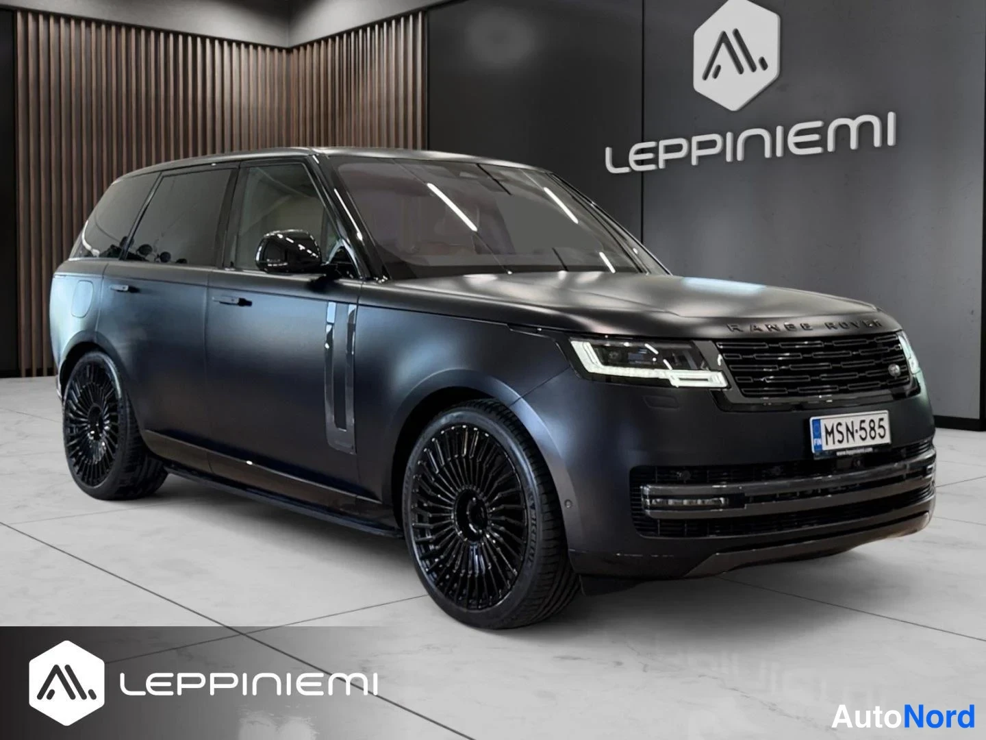 Etuviisto, nokka oikealle: Auton etukulma oikealta kuvattuna, tummanharmaa Range Rover mattapintaisella maalilla ja mustilla kevytmetallivanteilla sisätiloissa.