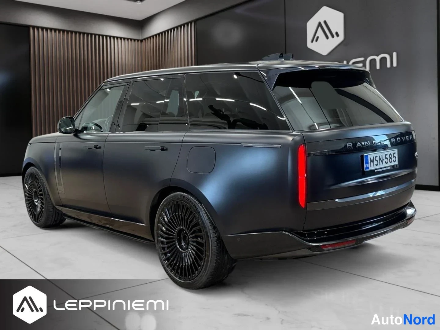 Takaviisto: Musta Land Rover Range Rover takaa kulmakuva myyntitilan lattialla, rekisteritunnus.