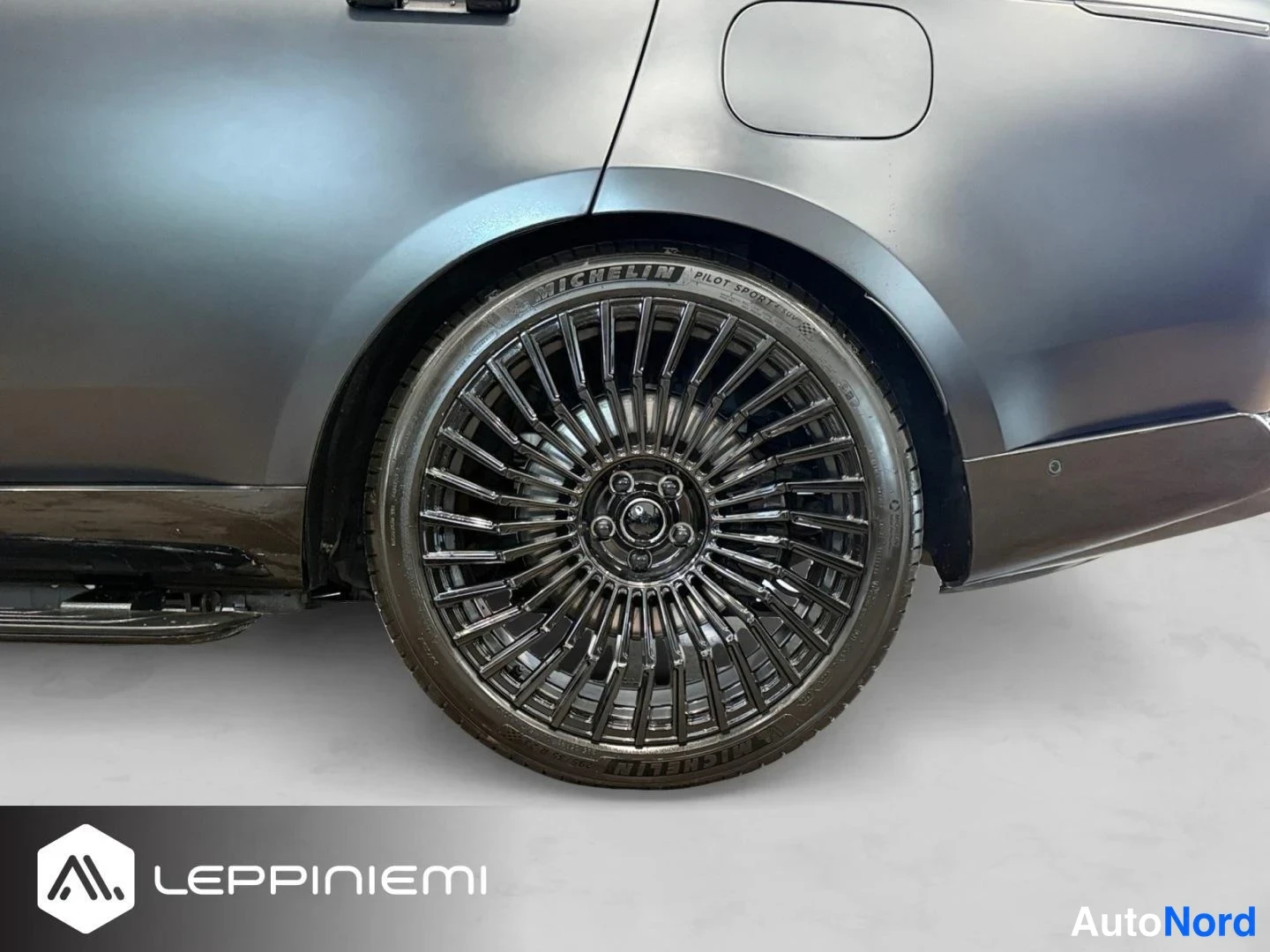 Sivulta: Auton takapyörä ja takalenkki lähikuvassa: tummagrafiittinen vanteleva kevytmetallivanne, Michelin Pilot Sport -rengas ja tummanharmaa kylkipaneeli polttoainetä