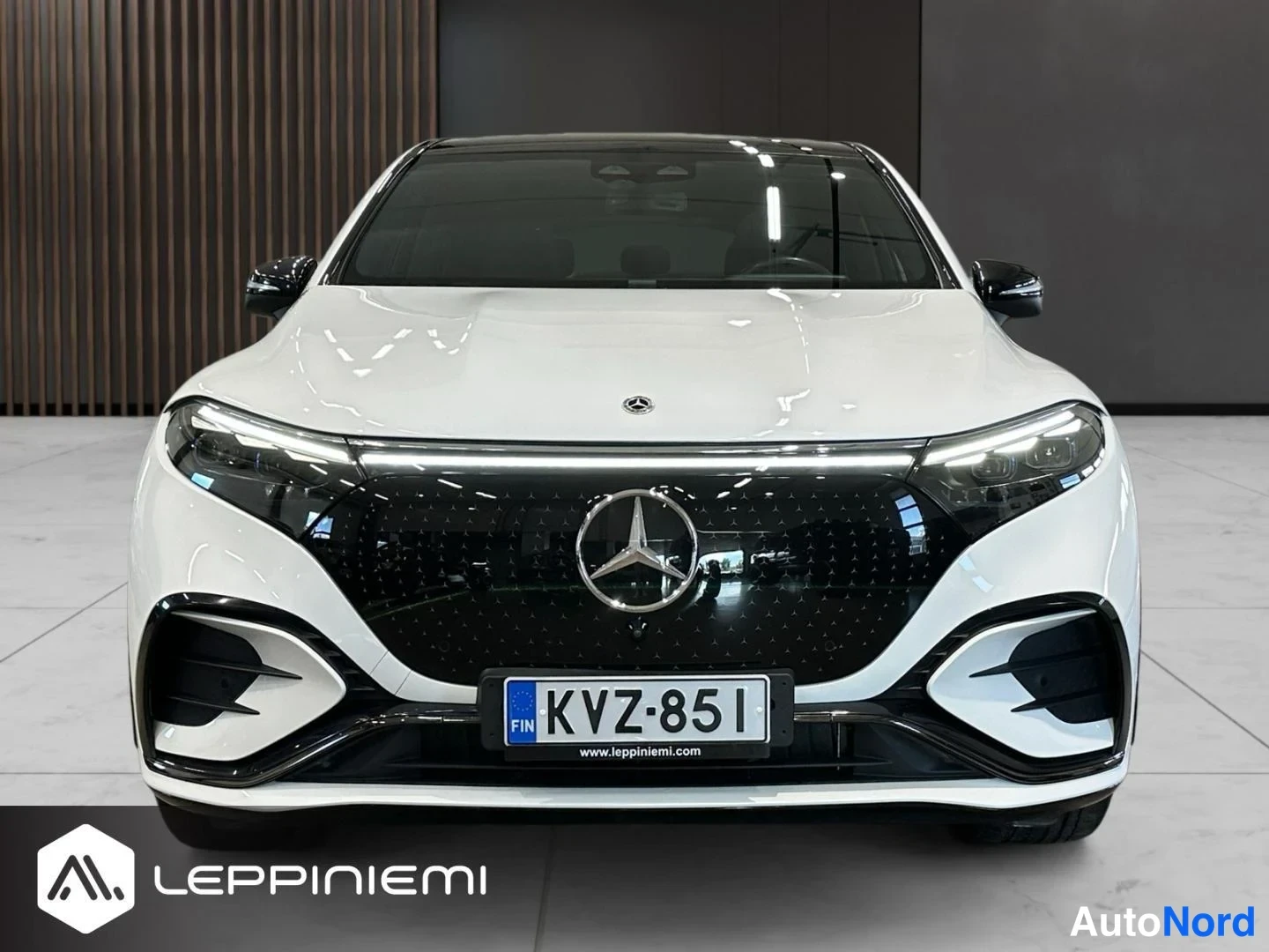 Edestä: Mercedes-Benz EQS SUV suoraan edestä kuvattuna, valkoinen korit, musta valaistu etusäleikkö ja rekisteritunnus.