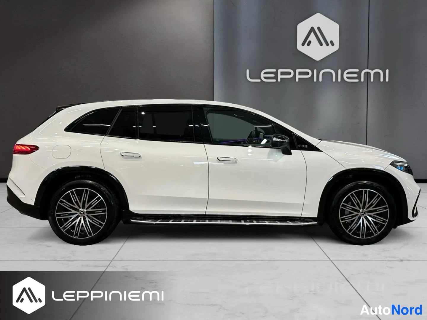Sivulta: Mercedes-Benz EQS SUV:n sivuprofiili valkoisena, kuvattuna oikealta sivulta sisätiloissa.