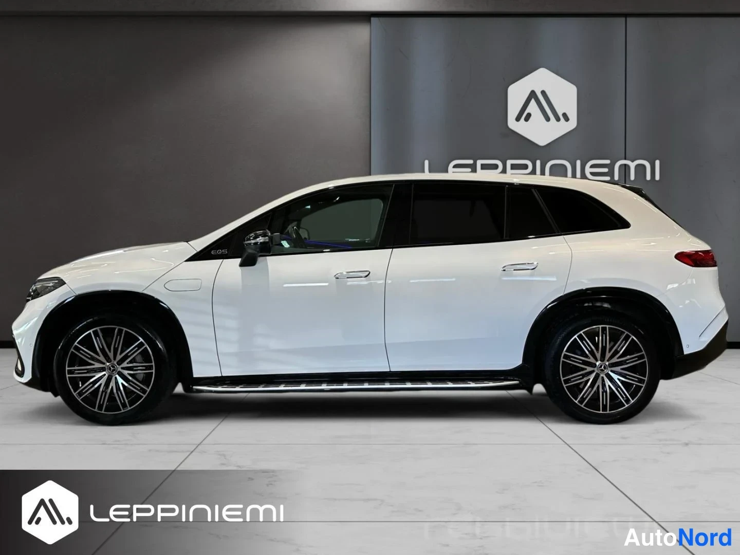 Etuviisto, nokka vasemmalle: Valkoinen Mercedes-Benz EQS SUV sivusta kulmakuva, nokka vasemmalla, metallivanteet ja kromiset ovikoristeet.