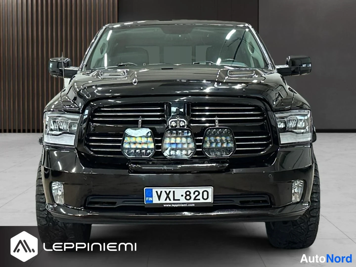 Edestä: Mustan lava-auton etupää suoraan edestä, kolme LED-lisävaloa ritilän edessä, rekisteri.