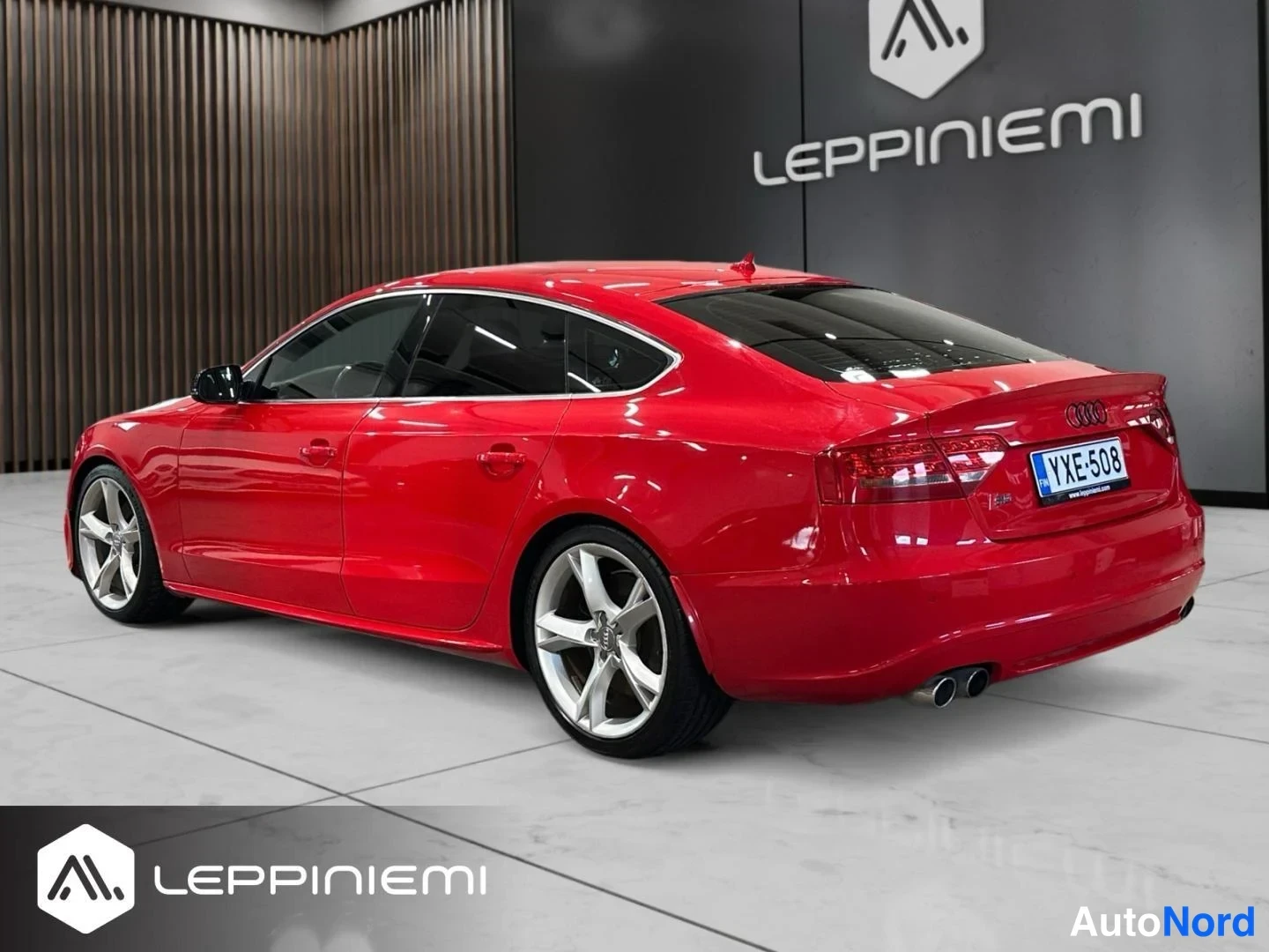 Takaviisto: Auton takakulma, punainen Sportback-koria takavaloineen ja rekisteritunnisteella, sisätiloissa.