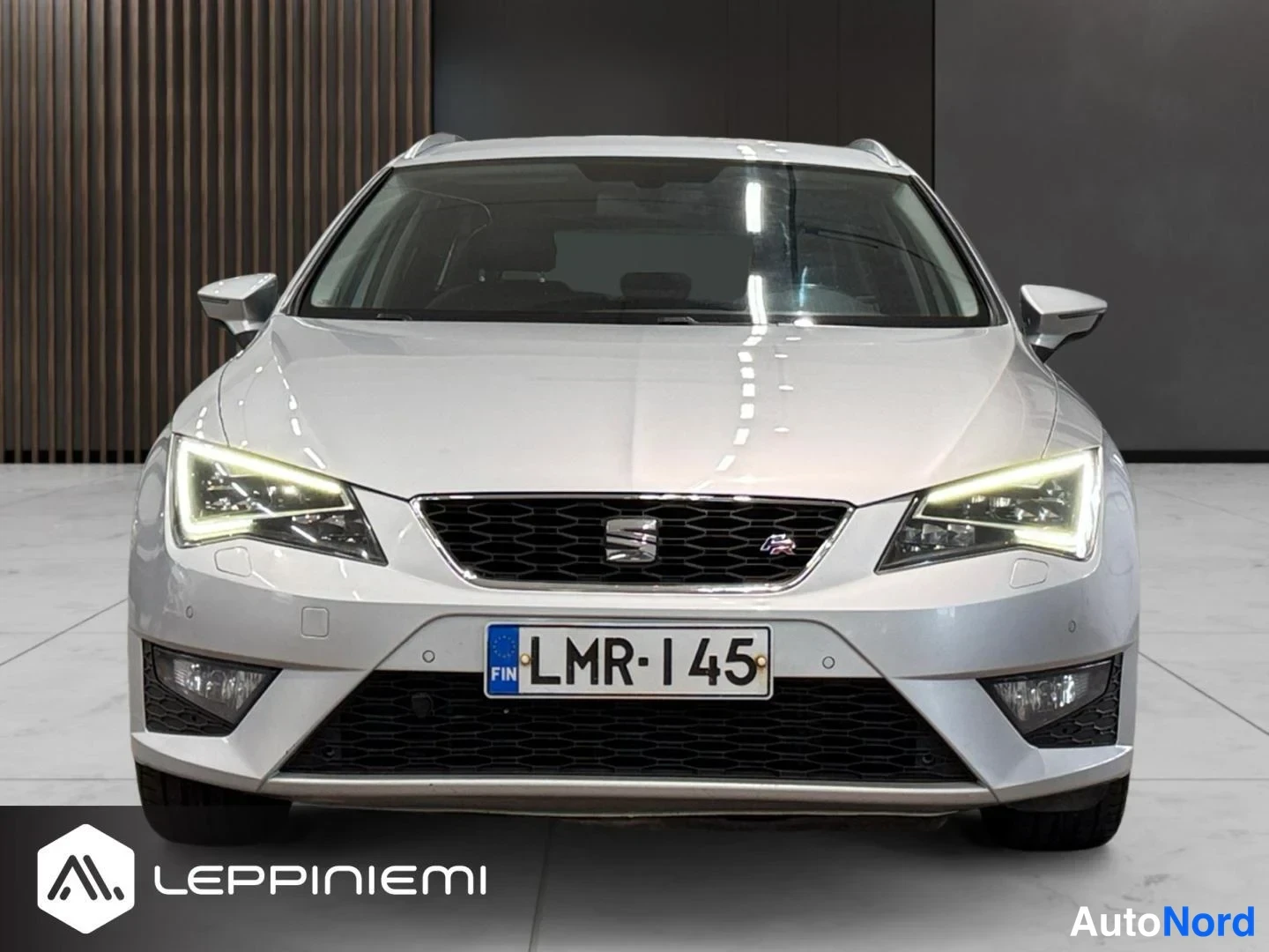 Edestä: Etunäkymä hopeanvärisestä Seat Leon ST -farmariautosta; musta etusäleikkö SEAT-merkillä, LED-päiväajovalot ja rekisterikilpi.