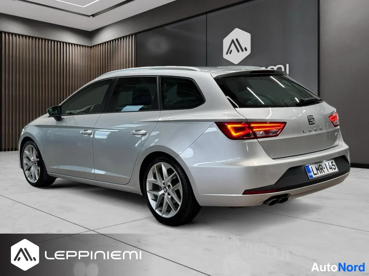 Takaviisto: Seat Leon ST -farmarin takakulma oikealta kolmesta neljäsosasta; hopea koriväri luettavissa koripaneeleista ja ovista, tunnistekilpi takaluukussa.