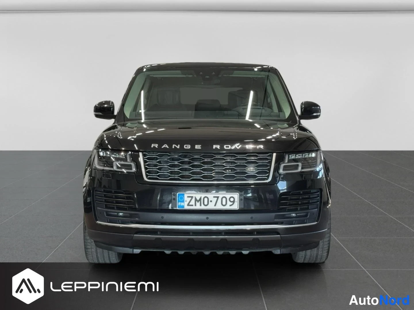 Edestä: Mustan Range Rover -maastauton suora etunäkymä, molemmat ajovalot ja etusäleikkö näkyvissä, rekisterikilpi ZM0-709.