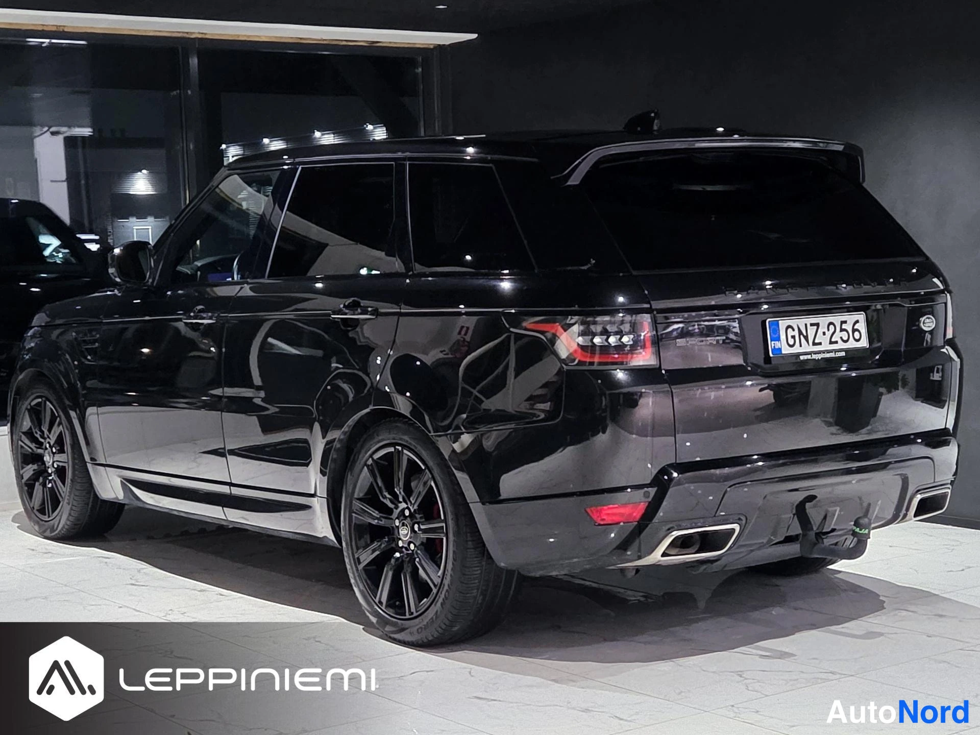 Takaviisto: Mustan Range Rover Sportin takaviisto oikealta, kylkiviiva, takavalo, rekisterikilpi ja mustat vanteet näkyvissä.